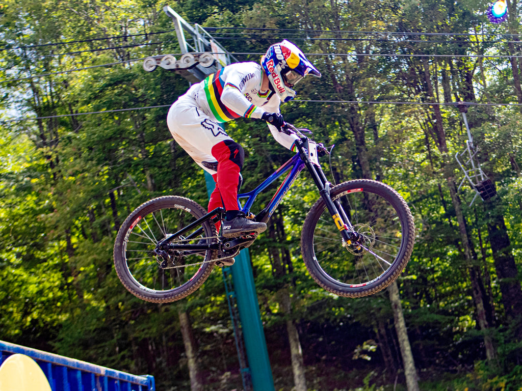 Photo credit Jetsun RPM, copyright. Photograph of mountain bike racer in the air during the 2021 UCI Downhill World Cup and World Championship events at Snowshoe Bike Park and Resort in West Virginia, USA.